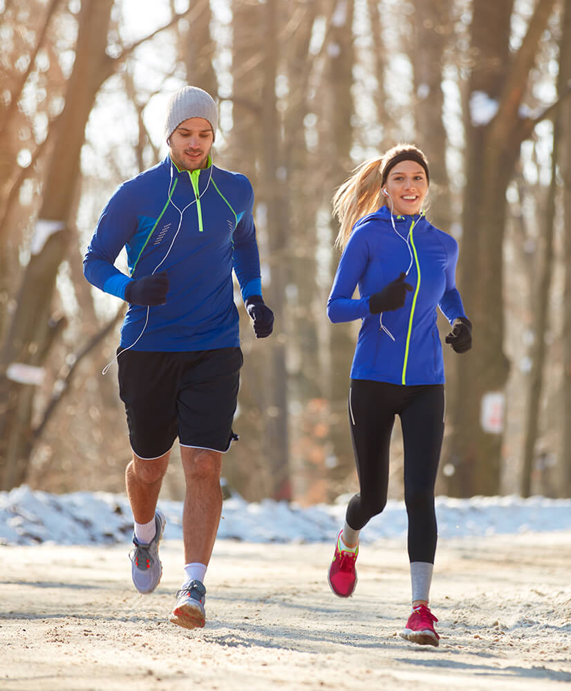 two people jogging along path in the snow wearing matching blue jackets
